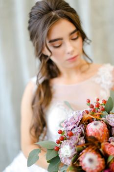 Portrait of beautiful caucasian brunette caucasian bride with bouquet flowers at studio. Concept of bridal photo session and beauty.