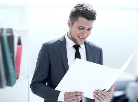 Smiling businessman reading some documents in workplace