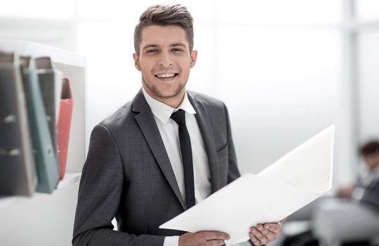Portrait of cheerful businessman dressed in stylish formal wear holding folder with financial documents in hand and smiling at camera