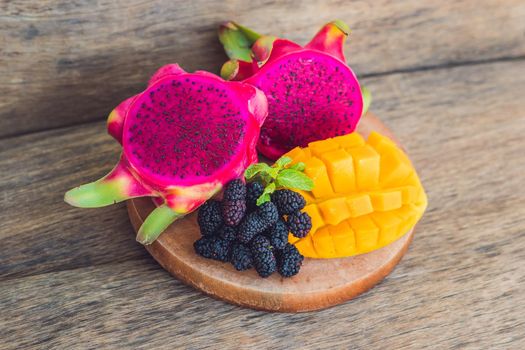 Sliced dragon fruit and mango on an old wooden background.