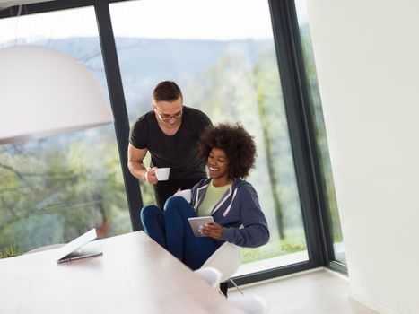 young multiethnic romantic couple enjoying morning coffee by the window in their luxury home