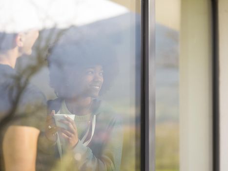 romantic happy young multiethnic couple enjoying morning coffee by the window in their luxury home