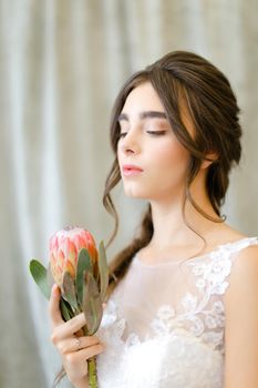 Portrait of pretty beautiful brunette caucasian bride with flowers at studio. Concept of bridal photo session and bridal makeup.