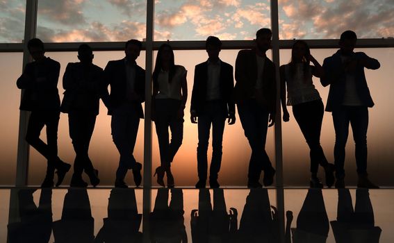 silhouette of a business team standing next to the office window. .photo with copy space