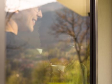 romantic happy young multiethnic couple enjoying morning coffee by the window in their luxury home