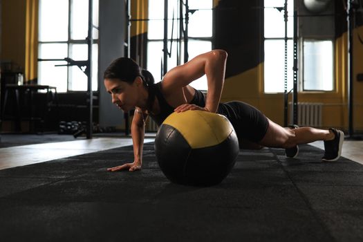 Fit and muscular woman exercising with medicine ball at gym