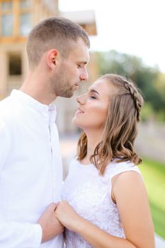 Groom kissing bride and holding hands outdoors. Concept of wedding and bridal photo session, relationship.