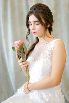 Portrait of beautiful brunette caucasian bride with flowers at studio. Concept of bridal photo session and bridal makeup.