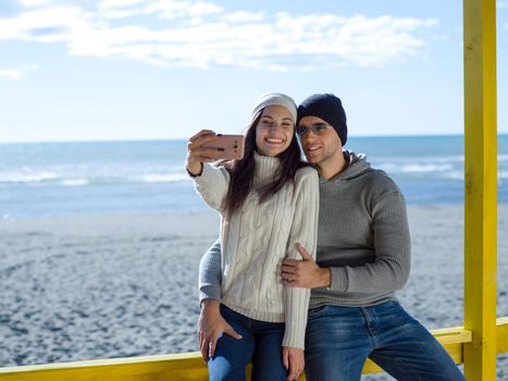 Very Happy Couple In Love Taking Selfie On The Beach in autmun day