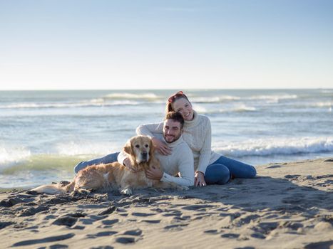 Couple With A Dog enjoying time  together On The Beach at autumn day