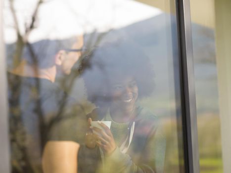 romantic happy young multiethnic couple enjoying morning coffee by the window in their luxury home