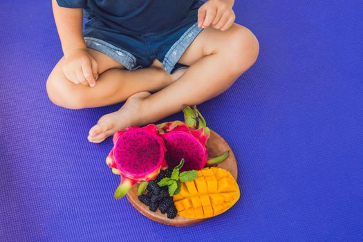Sliced dragon fruit and mango and boy in lotus pose.