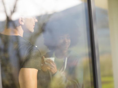 romantic happy young multiethnic couple enjoying morning coffee by the window in their luxury home