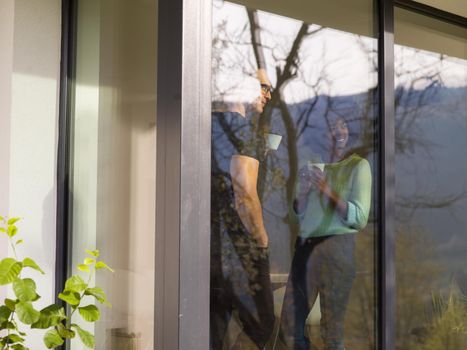 romantic happy young multiethnic couple enjoying morning coffee by the window in their luxury home