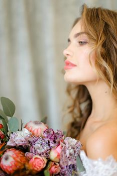 Close up portrait of caucasian bride with bouquet of flowers at studio. Concept of floristic art, beauty and beautiful wedding photo session.