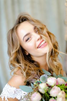 Close up portrait of young smiling bride with bouquet at studio. Concept of bridal photo session and floristic art.