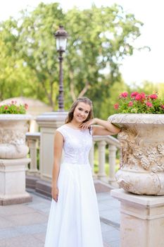 Caucasian bride standing near column and flowers. Concept of bridal photo session.