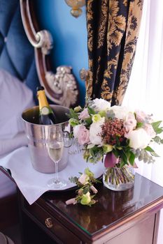 Bucket with champagne, wineglass and bouquet of flowers on table. Concept of decorations for celebrating wedding.