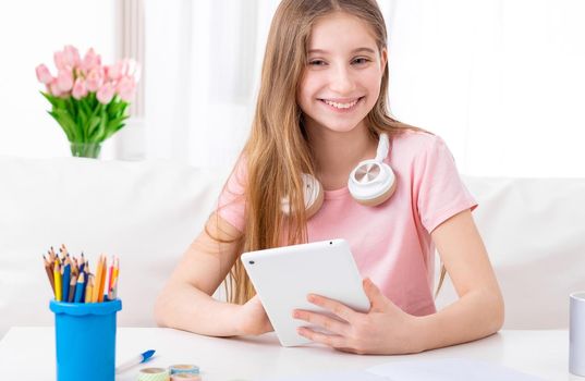 Girl is exploring social networks on her tablet at her working place indoors