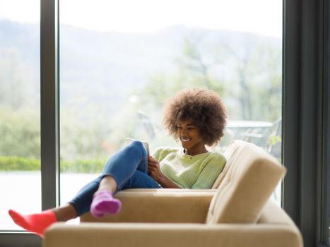 Young african american woman at home relaxing in her luxury lliving room reading a digital tablet  surf internet and work