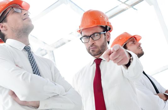 close up.a confident businessman in a safety helmet pointing at you.the concept of cooperation