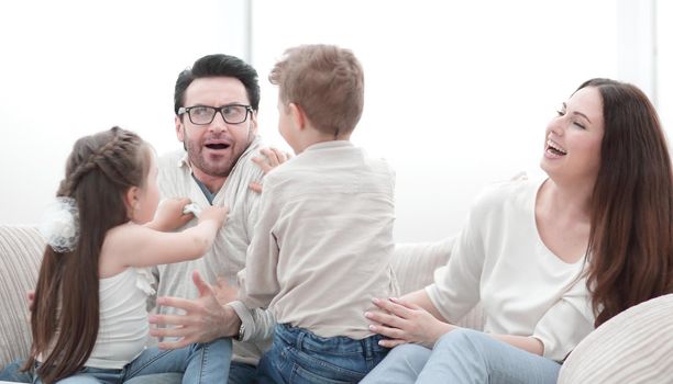 parents play with children sitting on the couch.the concept of family happiness