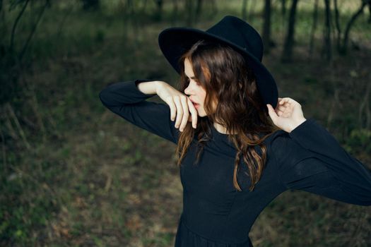 woman in the forest in a black hat gothic style Witch costume. High quality photo