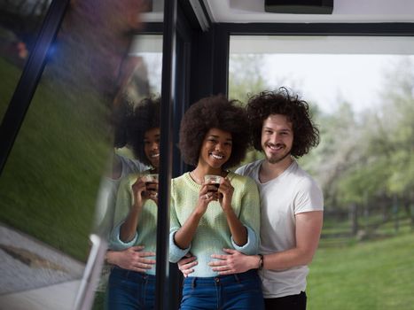 romantic happy young multiethnic couple enjoying morning coffee by the window in their luxury home