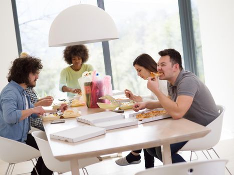 multiethnic group of happy friends spending time together with food and soda drinks, eating at home concept