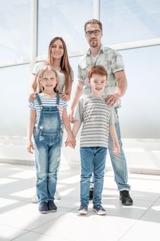 brother and sister with their parents standing in a spacious apartment .photo with copy space