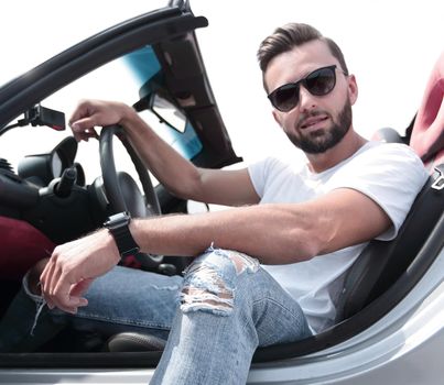 close up.stylish young man sitting in a luxury car .side view