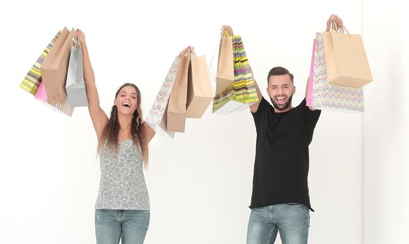 young couple holding shopping bags and looking at the camera isolated on white background