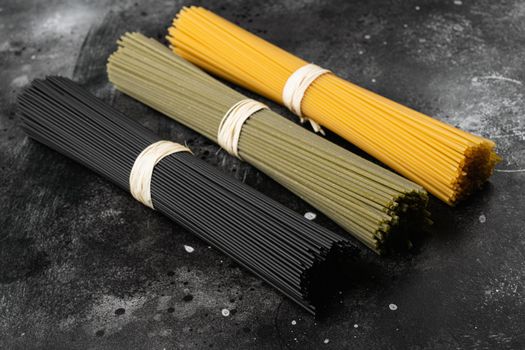 Dry colorful pasta spaghetti set, on black dark stone table background