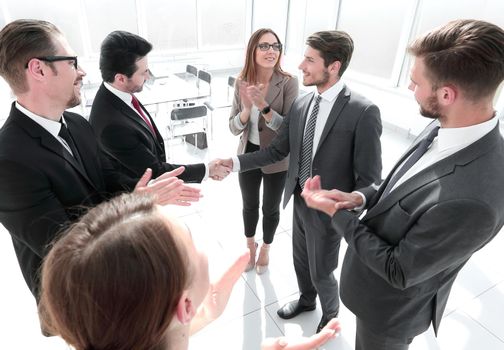 A confident business team of mixed ages and ethnicity making handshaking while meeting in a modern office. They are discussing ideas for their business development.