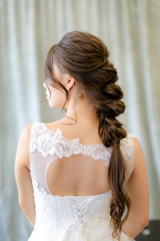 Back view of caucasian brunette bride with braid hair at studio. Concepf of bridal hair do and wedding.