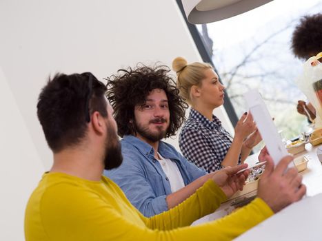 multiethnic group of happy friends spending time together with food and soda drinks, eating at home concept