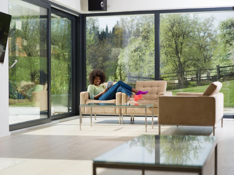 Young african american woman at home relaxing in her luxury lliving room reading a digital tablet  surf internet and work