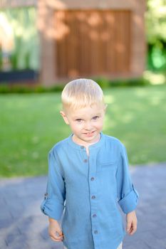 Little boy in jeans shirt standing on grass. Concept of kids and childhood.