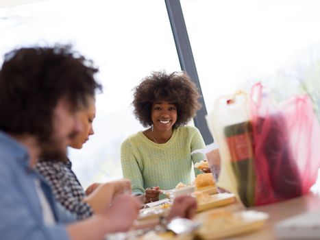 multiethnic group of happy friends spending time together with food and soda drinks, eating at home concept