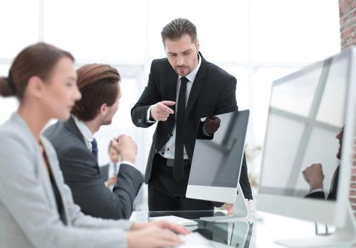 businessman talking with employees standing near the desktop.office weekdays