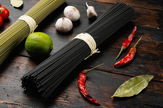 Raw uncooked black cuttlefish ink spaghetti set, on old dark wooden table background