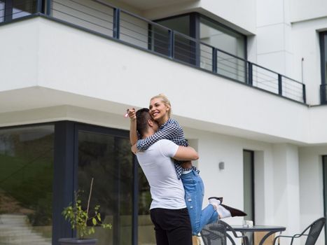 Portrait of a happy young couple hugging in front of their new luxury home villa