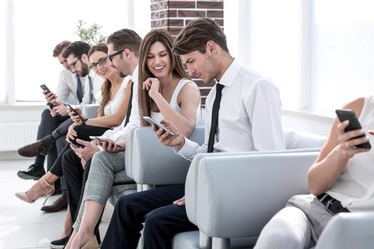 group of employees using their gadgets sitting in the office hallway .photo with copy space