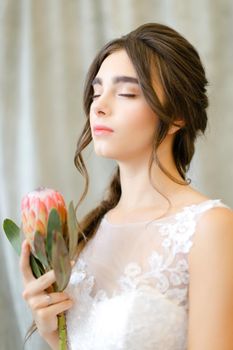 Portrait of nice beautiful brunette caucasian bride with flowers at studio. Concept of bridal photo session and bridal makeup.