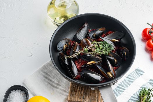 Mussels grilled with tomatoe sauce with herbs, on frying iron pan, on white background , with copyspace and space for text