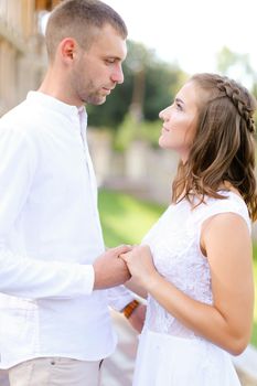 Bride and groom holding hands and standing outdoors. Concept of relationship, wedding and bridal photo session.