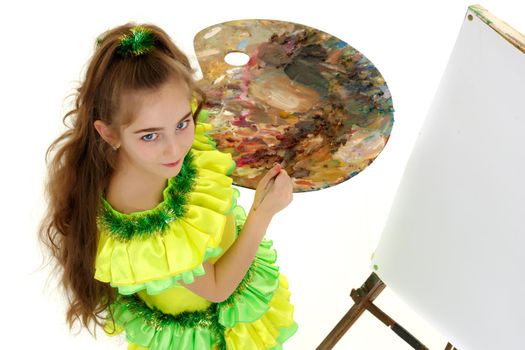 Cute little girl with a palette and a brush. The concept of children's creativity, learning to draw.