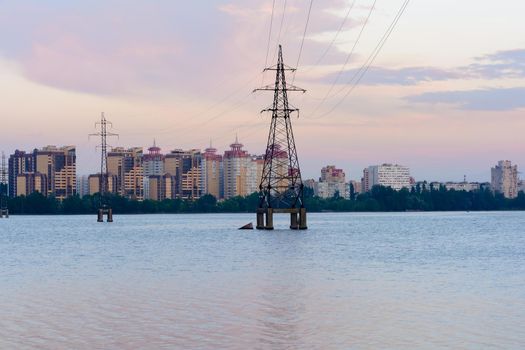 High-voltage power lines in water reservoir,high voltage electric transmission towers. Electrical power lines through a river at sunset. Voronezh Russia