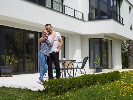 Portrait of a happy young couple hugging in front of their new luxury home villa