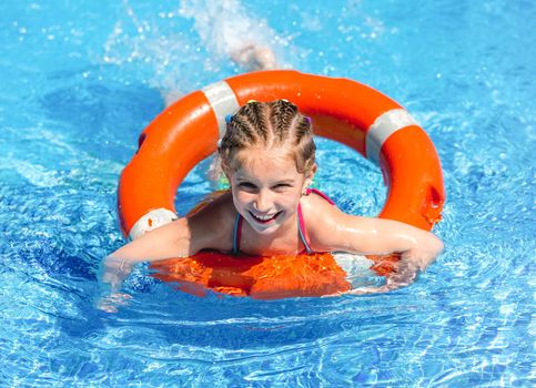 smiling little girl swims with a lifeline in the pool in summer